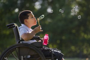 Hispanic boy in wheelchair blowing bubbles