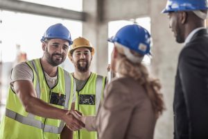Construction worker and executive shaking hands in construction site